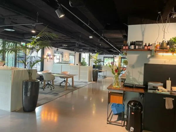 Moderne kantoorruimte aan de De Cuserstraat met open werkplekken, groene planten en een koffiehoek.